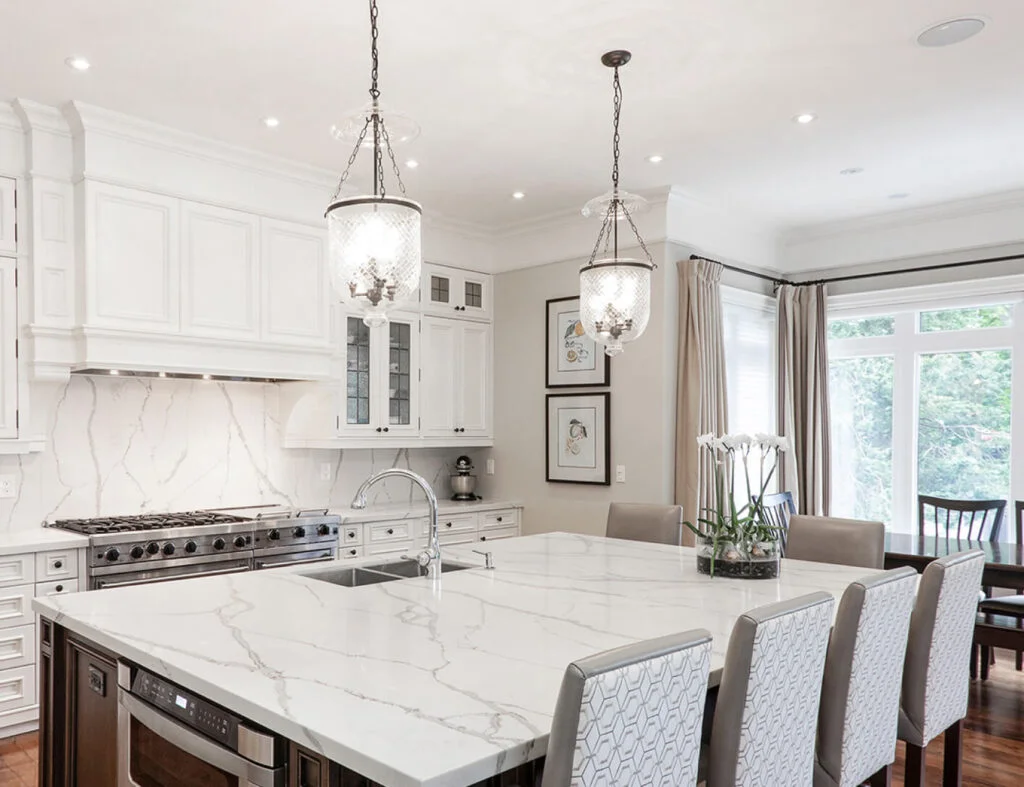 A spacious home kitchen featuring elegant marble counter tops and a generous island.