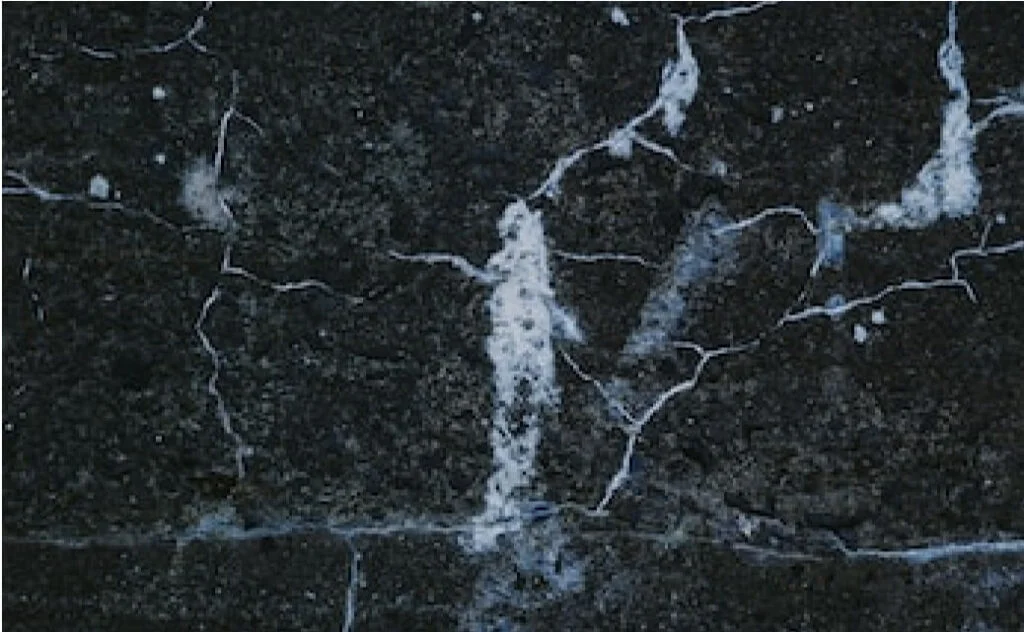 A black marble tile with quartz cracks on it.