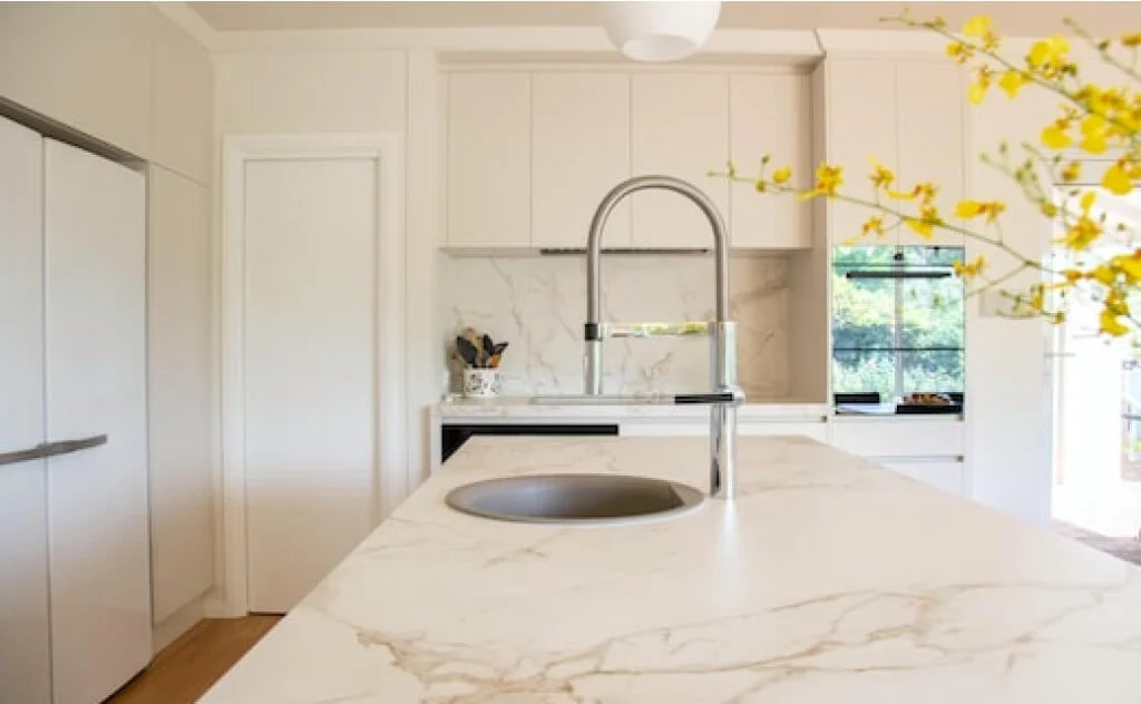 A kitchen with quartzite countertops and yellow flowers.