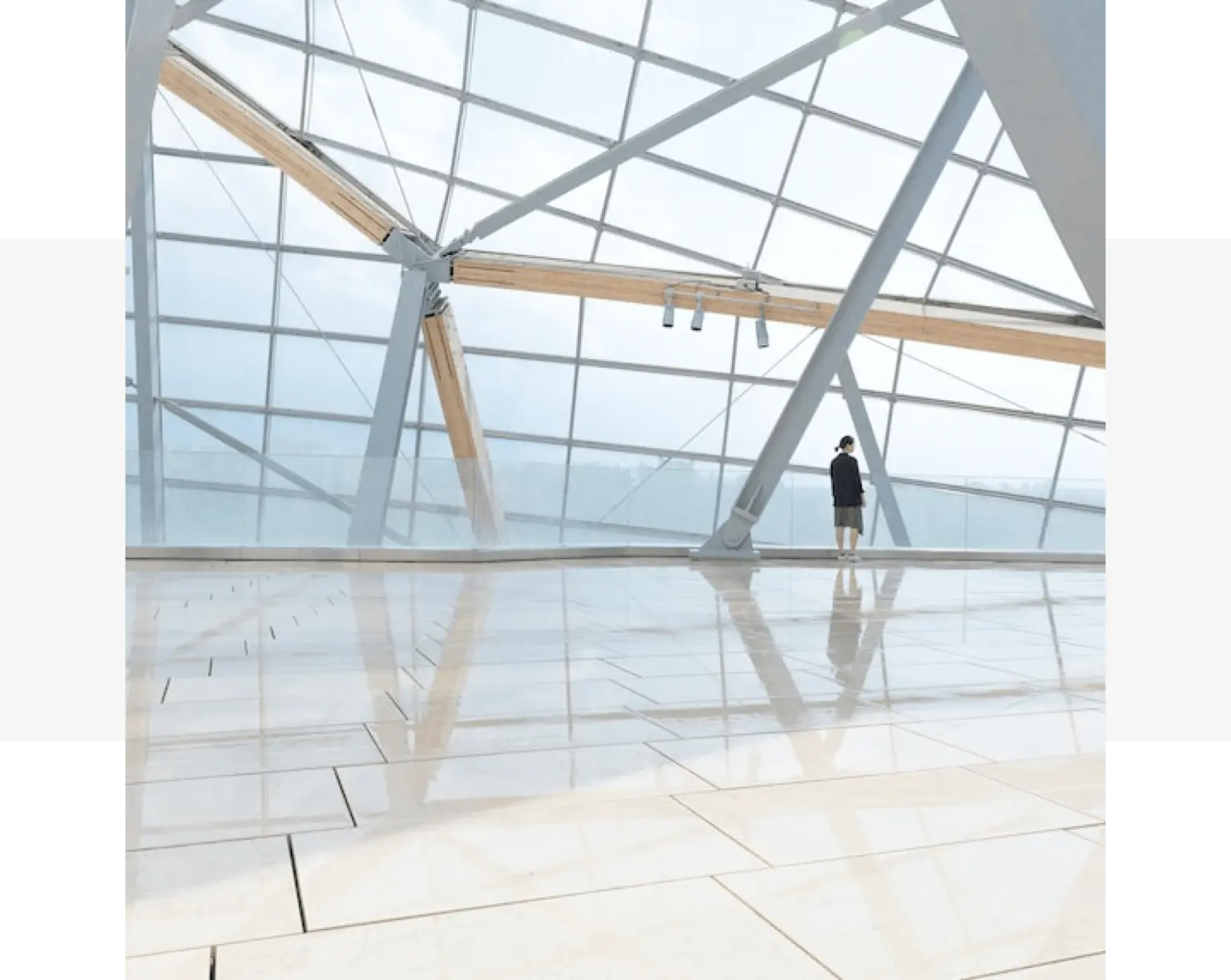 A person is standing in a glass building with grey quartz benchtops.