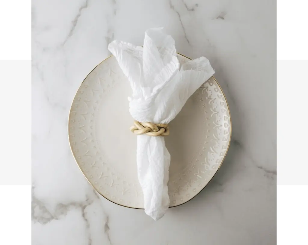 A grey napkin with a rope tied around it on a plate.